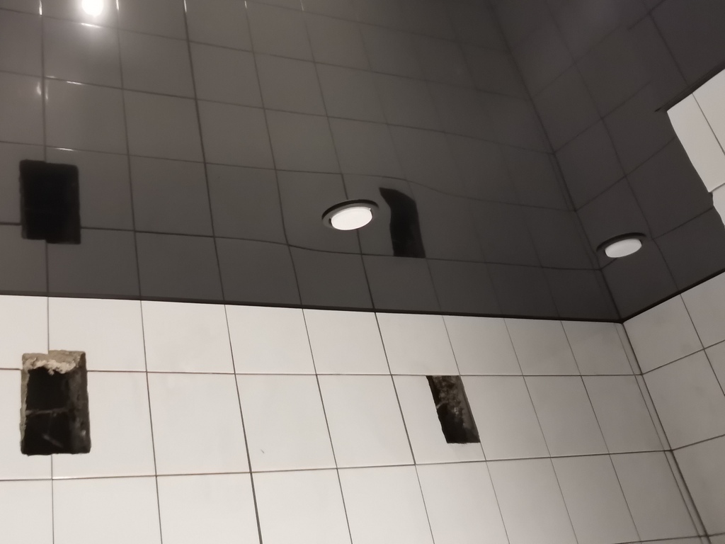 Зеркальное отражение в чёрном глянцевом натяжном потолке в ванной комнате